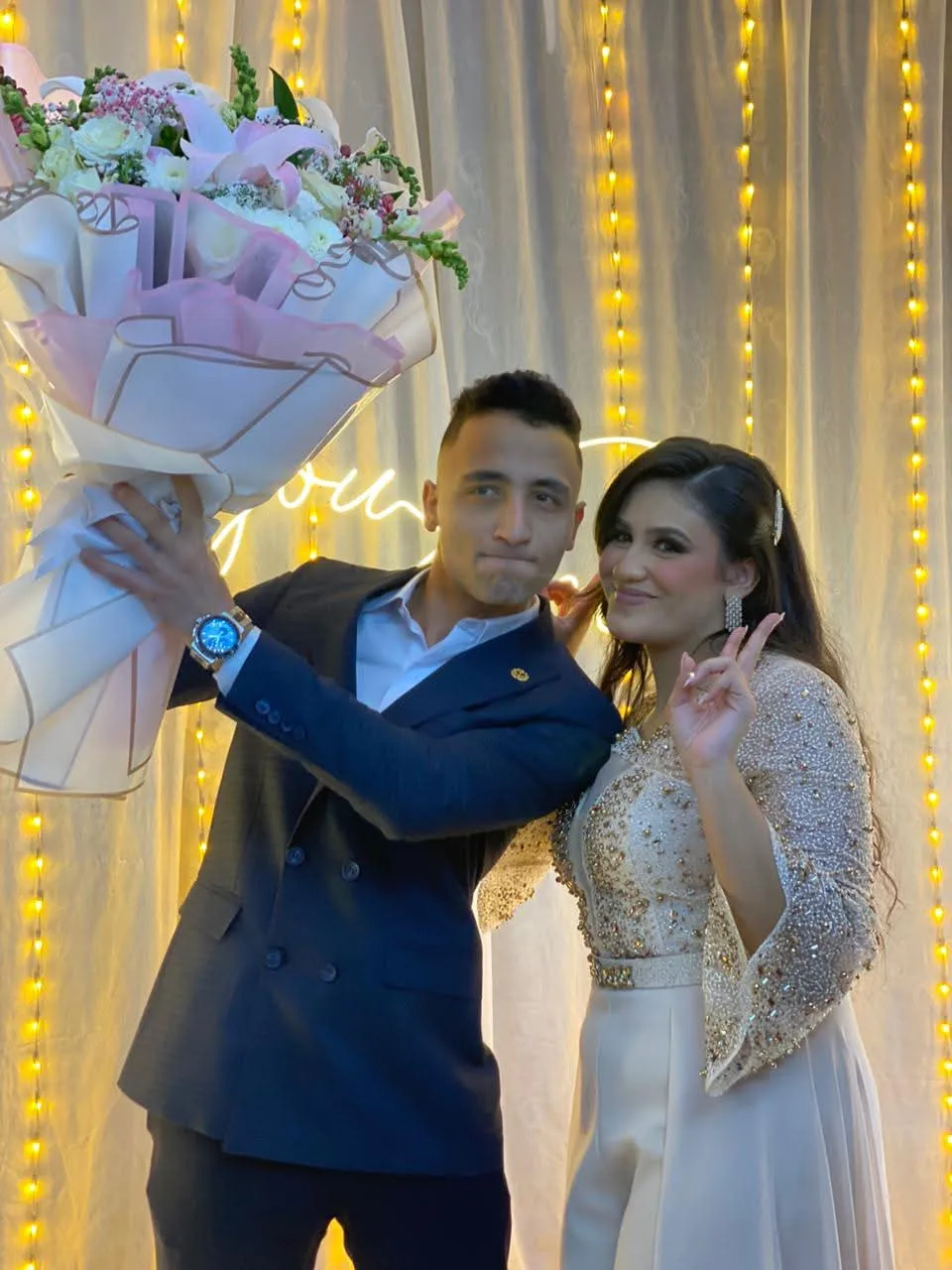 Muhammed and Merna celebrating with a bouquet of flowers